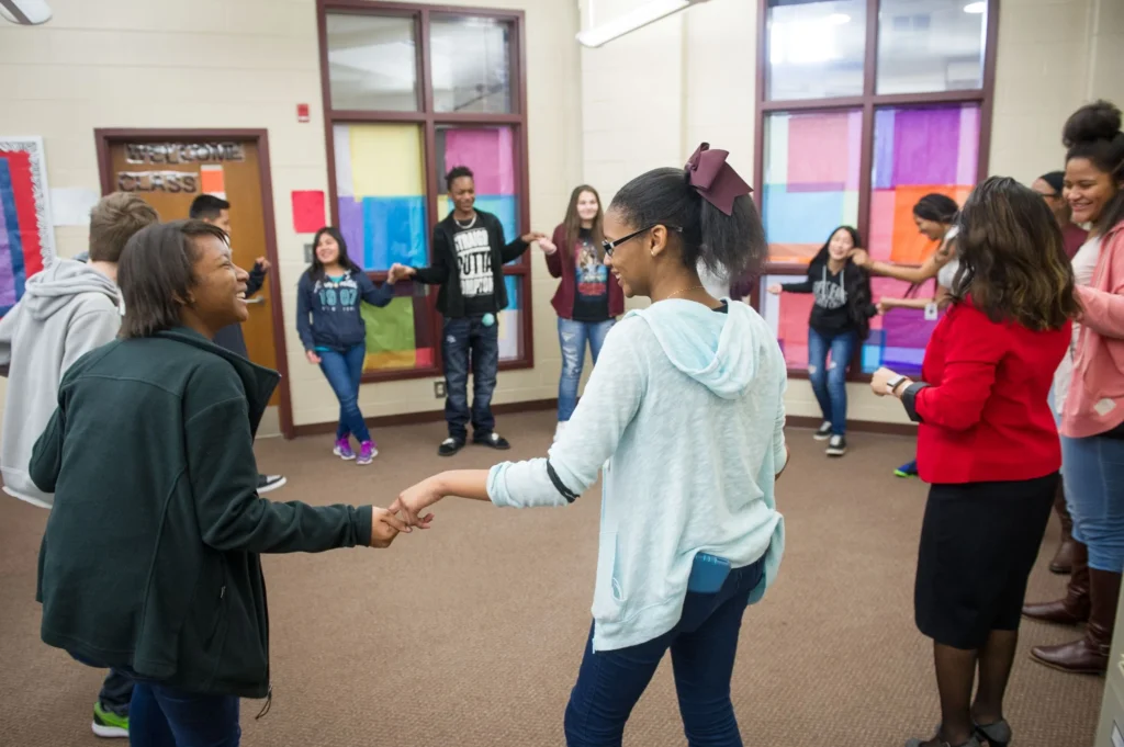 Middle school students are smiling and standing in a circle for Responsive Advisory Meeting