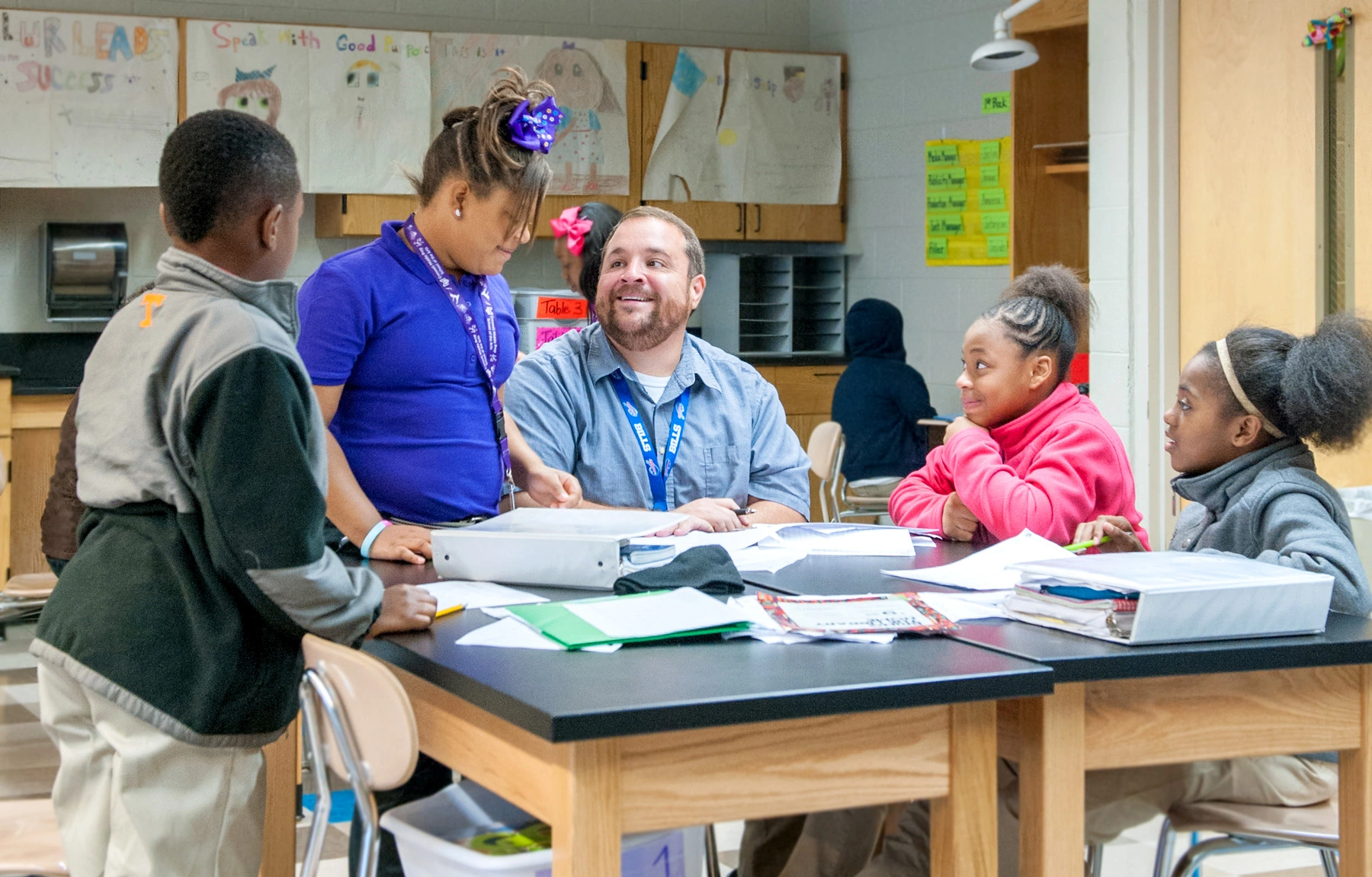 A group of students and their teacher are working together at a table.