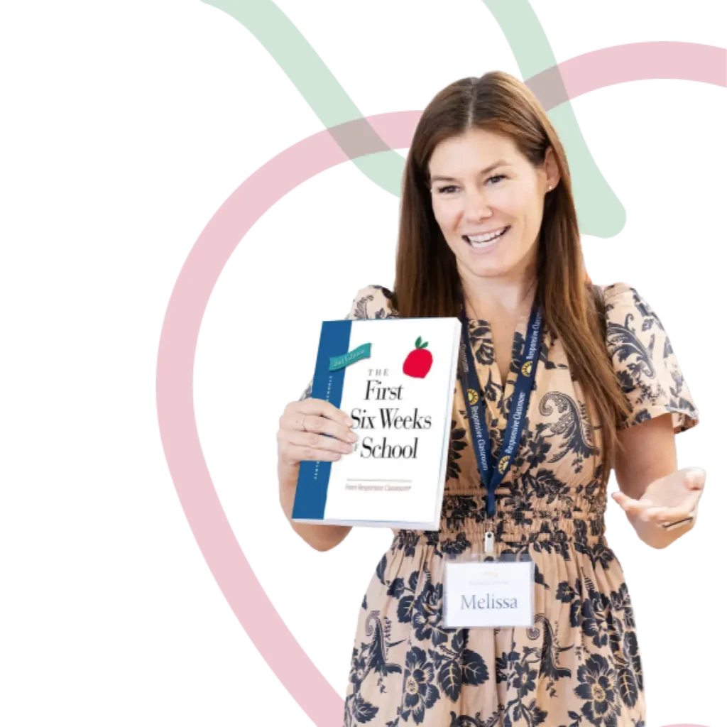 A Responsive Classroom presenter holding the First Six Weeks of School book standing in front of the First Six Weeks of School Conference apple logo.